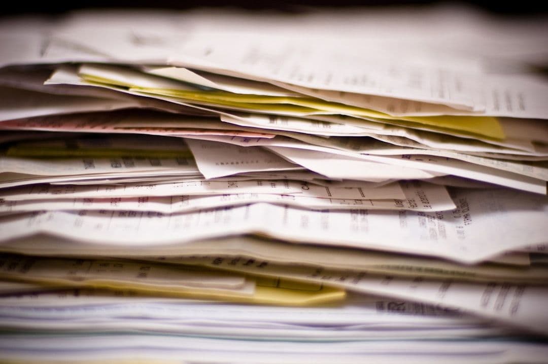 A recruiter reviewing a large stack of resumes at a desk
