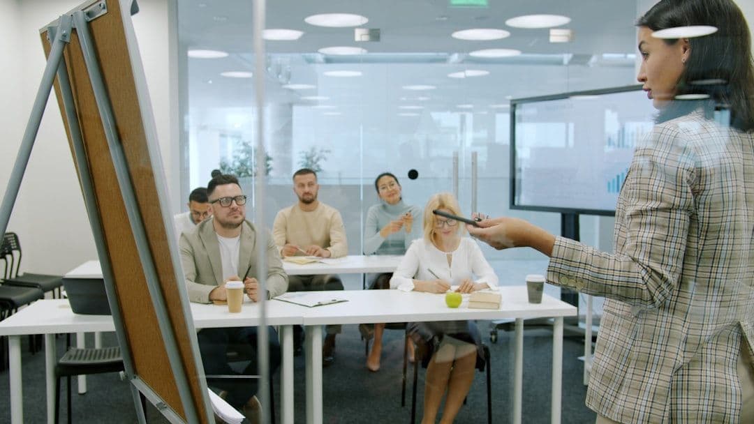 A teacher writing on a whiteboard in a bright classroom setting