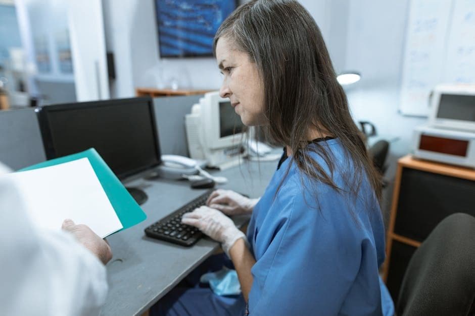 A nurse reviewing documents on a computer at a hospital workstation
