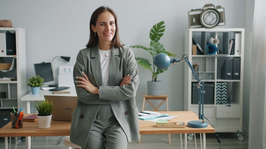 A professional woman sitting at a desk, confidently writing or reviewing a resume on her laptop