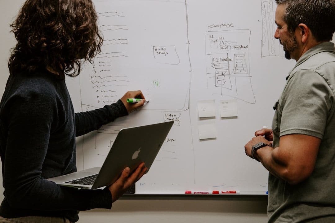 Engineer drawing system architecture on a whiteboard during a technical planning session