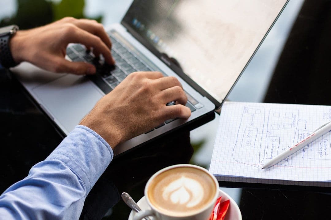 Professional reviewing their resume on a laptop at a desk with a cup of coffee nearby