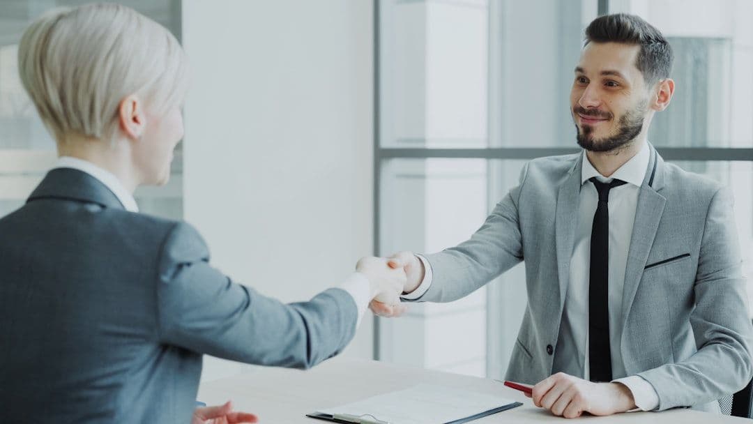 Professional handshake between two people in business attire, representing successful career transition