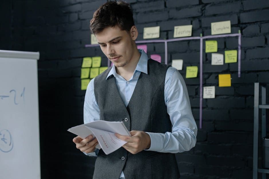 A project manager reviewing printed project documents at a desk, focused and analytical