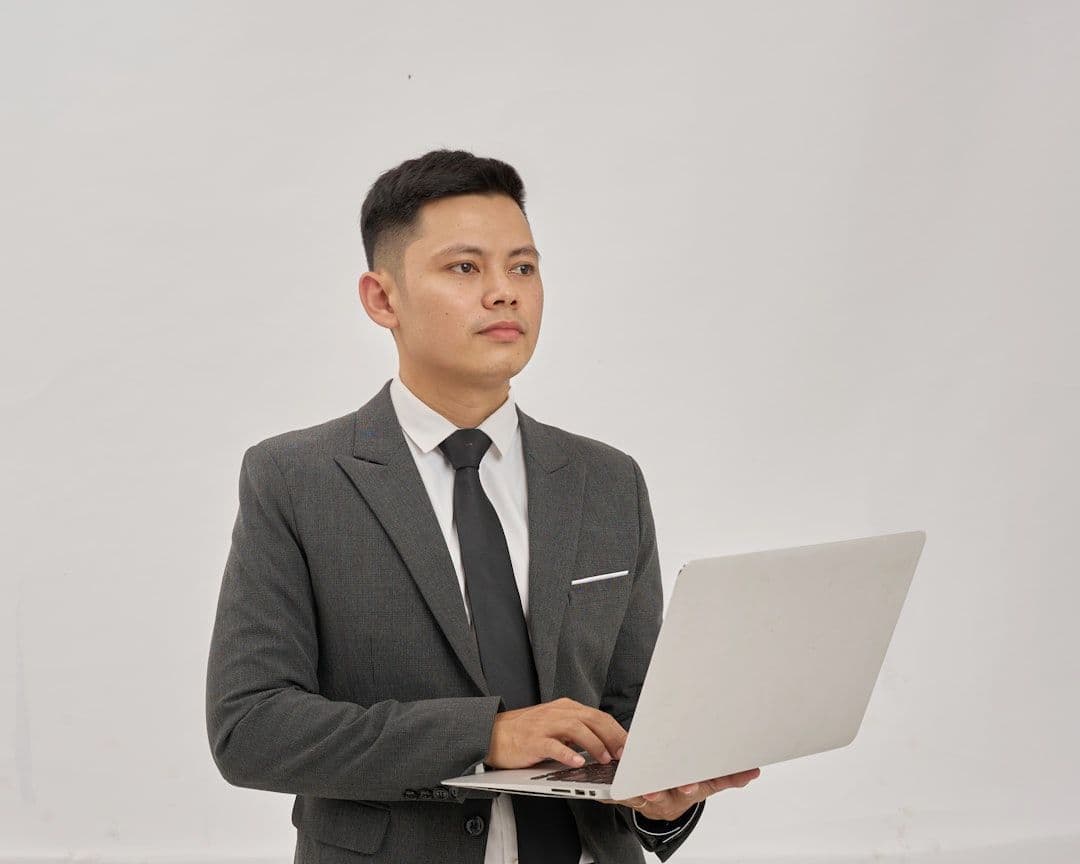Professional reviewing resume documents at desk with laptop